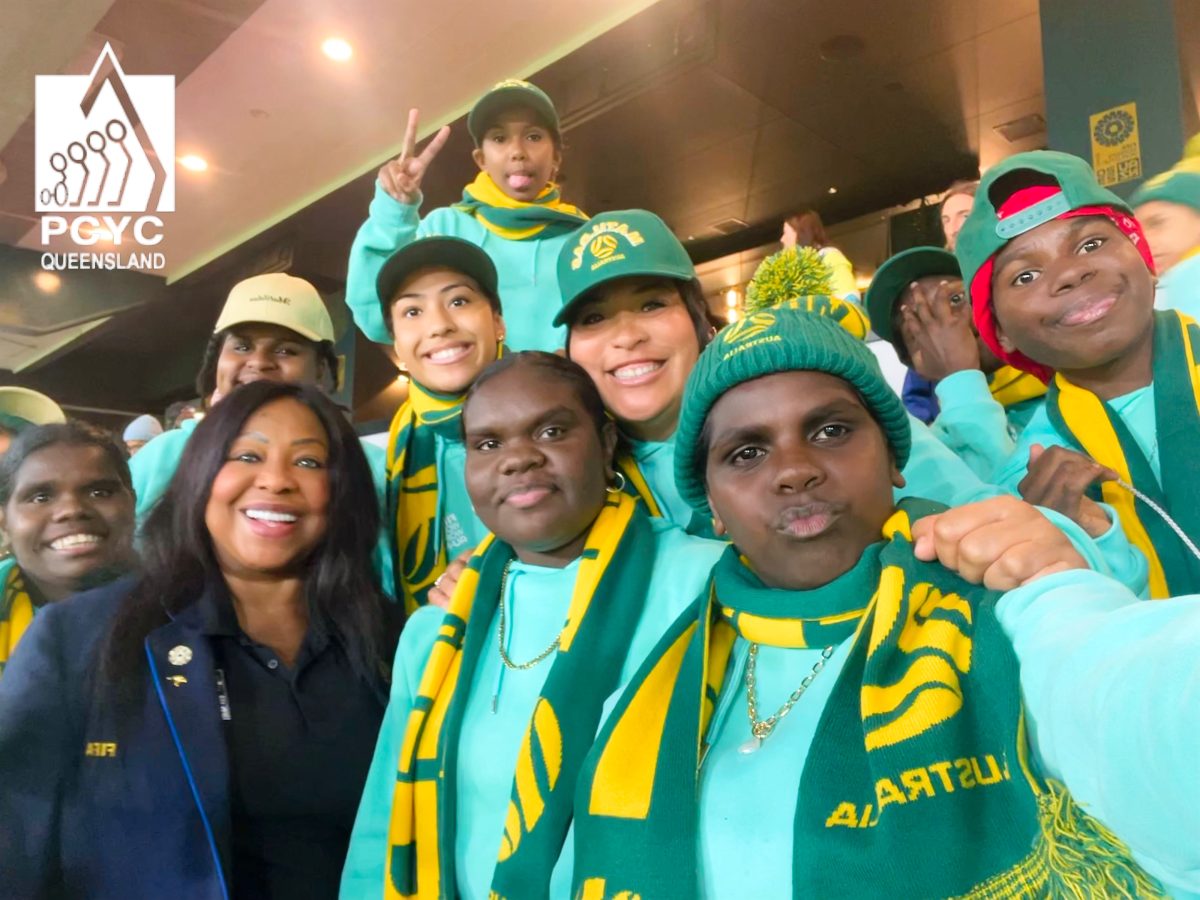 The eight women are smiling for a selfie with the FIFA secretary general. The girls are wearing matching teal hoodies and green and yellow beanies and scarves.