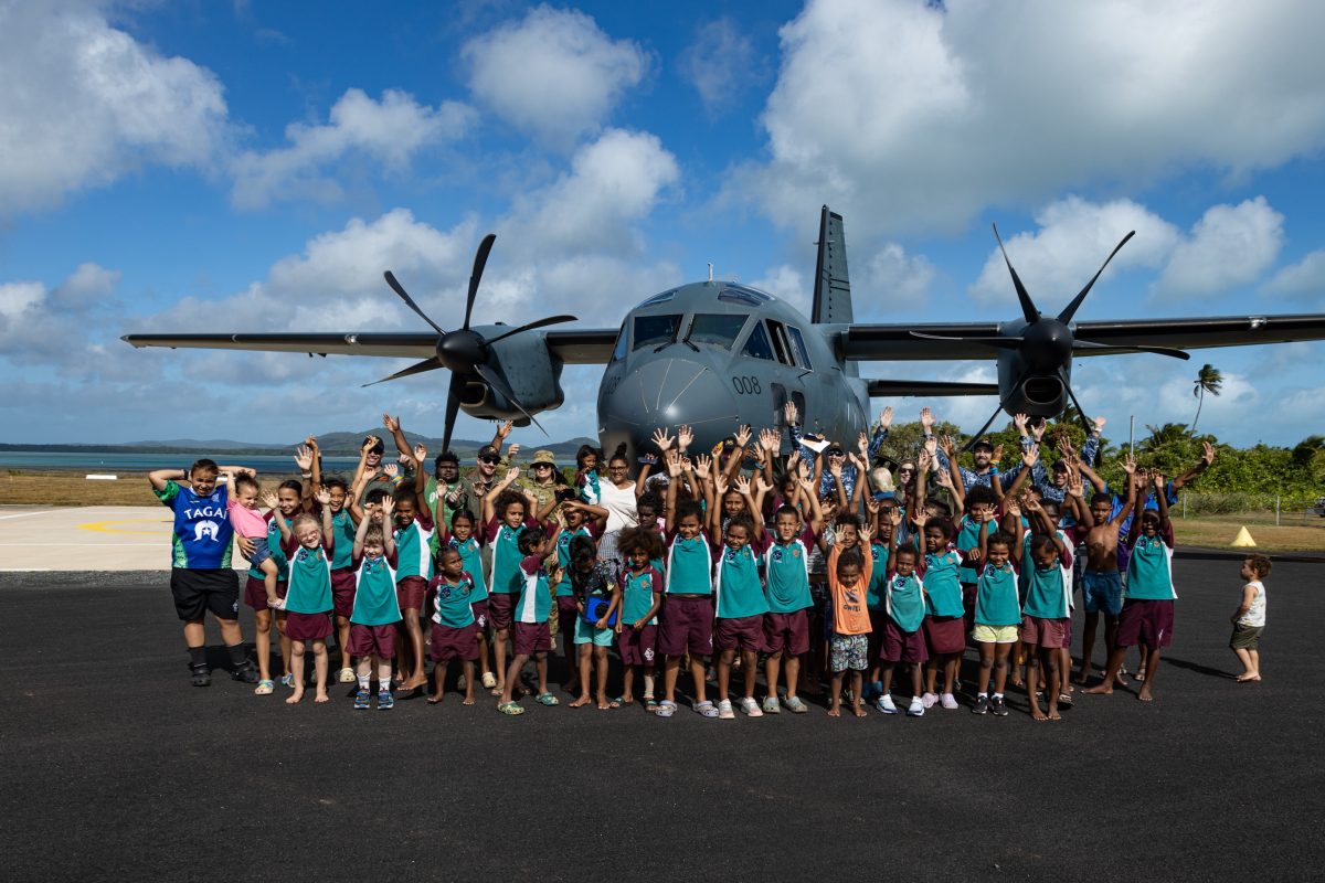 A group photo including the Australian Airforce, Army and Badu community who cheered the arrival of the C-27J Spartan. They are all standing in front of the aircraft.