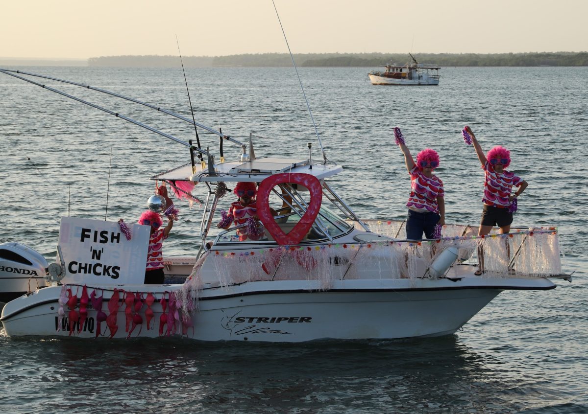 Lady anglers dressed in pink standing on a boat on the water decorated in pink.