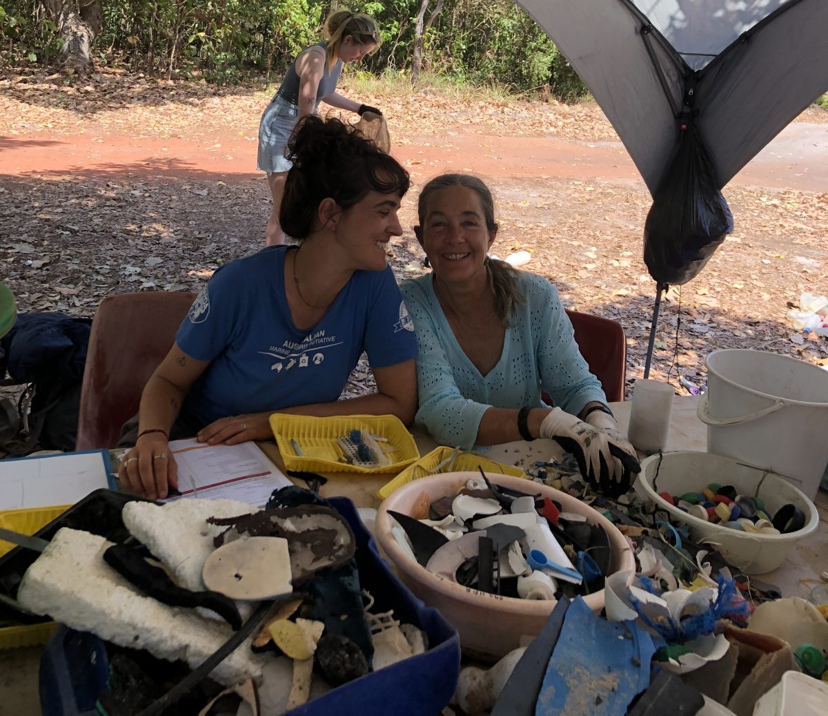 Two women are sitting at a table sorting debris found on the day.