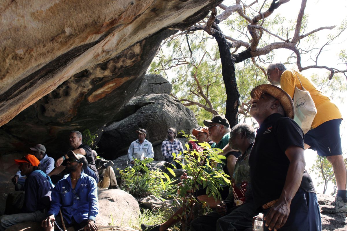First Nations men look at Aboriginal rock art.