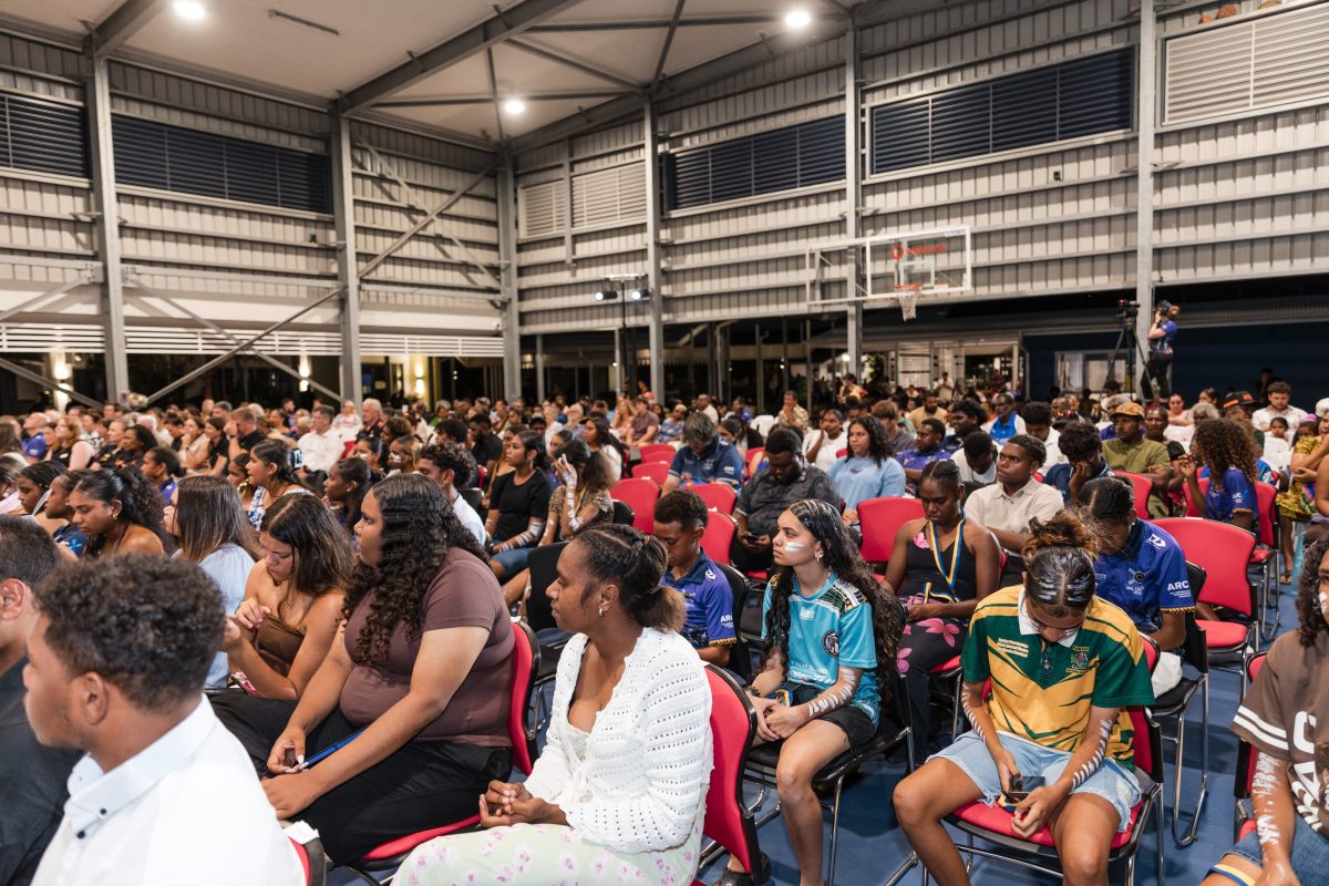 crowd of peolple seated in a sports hall.