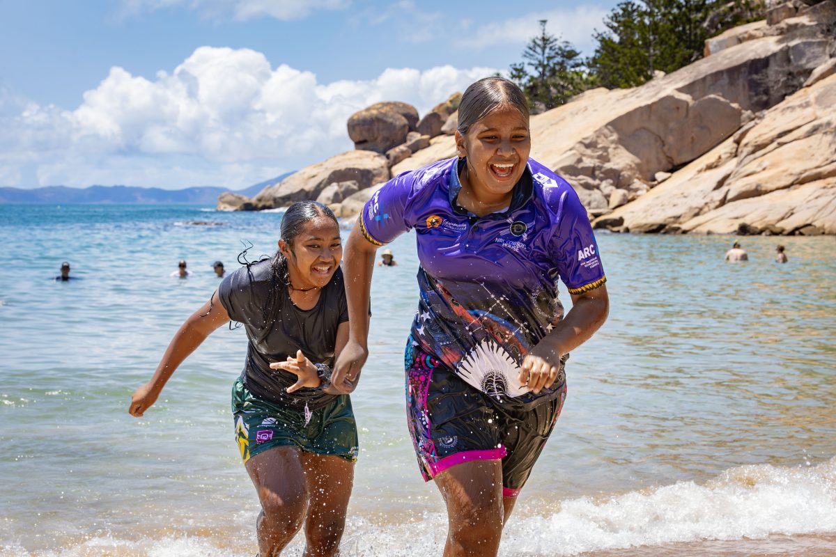 Two girls run from the surf.