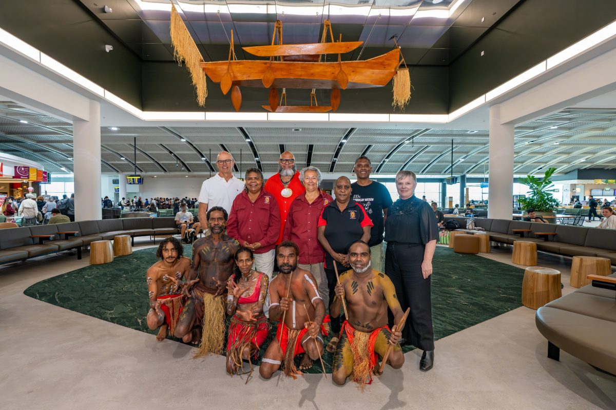 Group of 12 pose under canoe sculpture