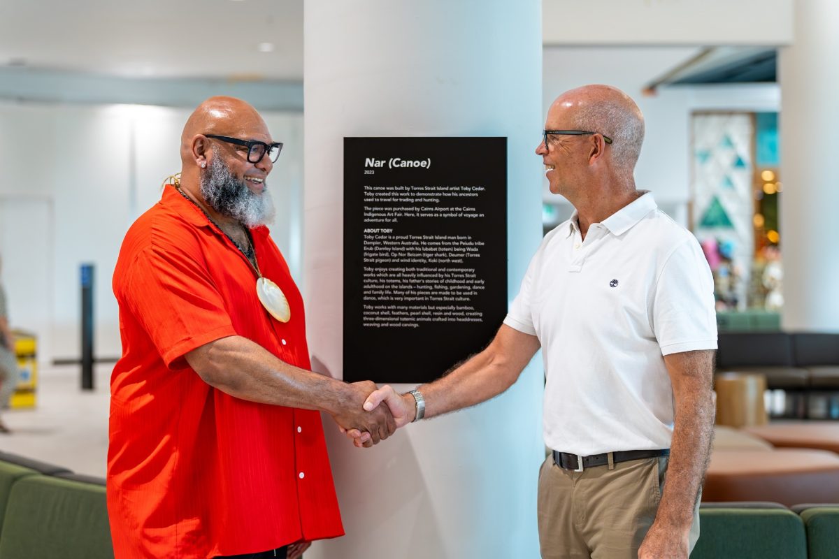 Torres Strait Island artist Toby Cedar and Cairns Airport CEO Richard Barker shake hands.