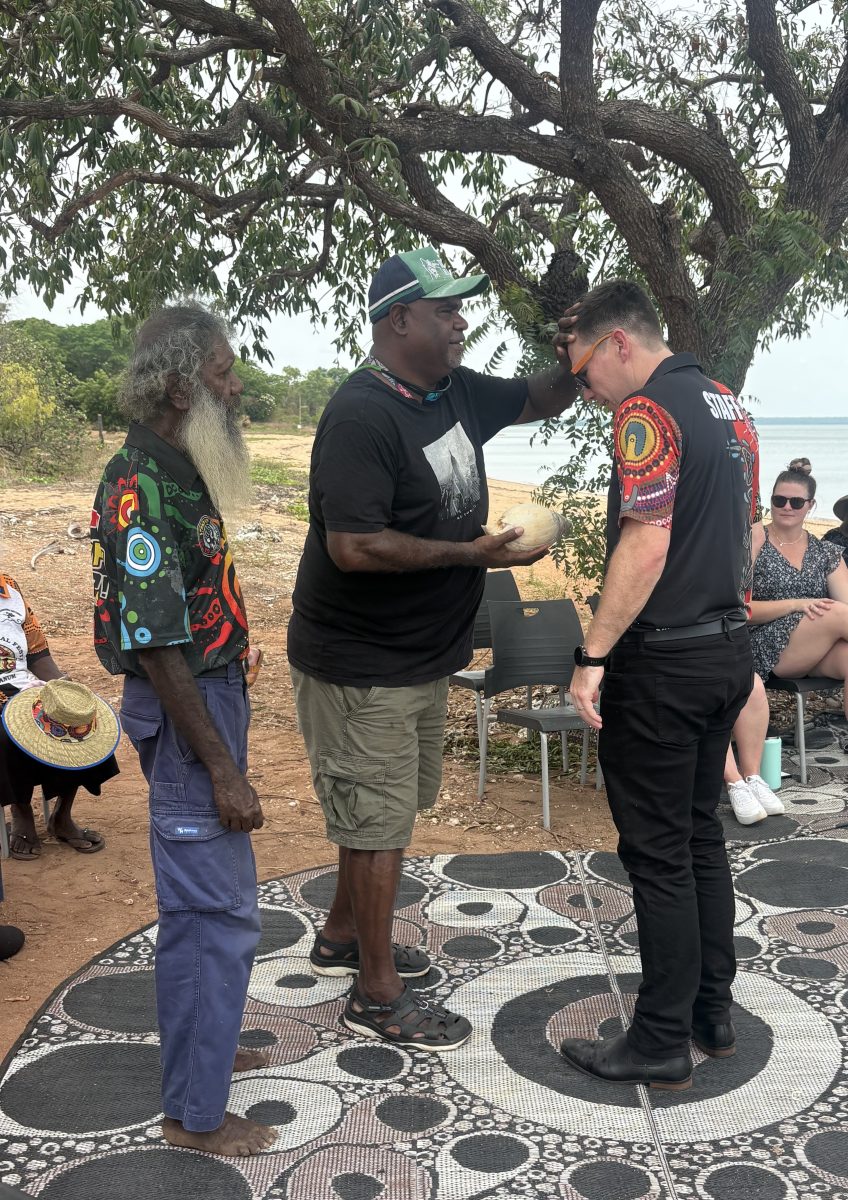 Ernest Madua performs water blessing on new secondary principal Jarrod Prakelt