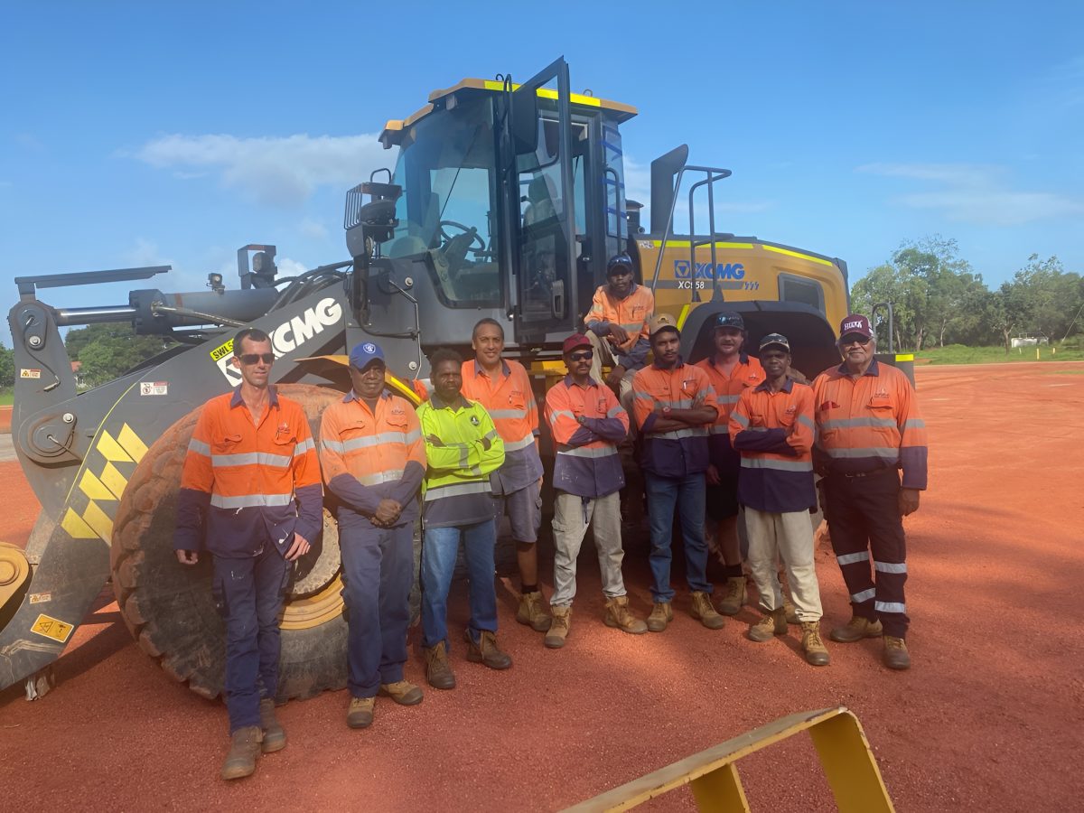 Aurukun Shire Council staff stand in front of a grader.